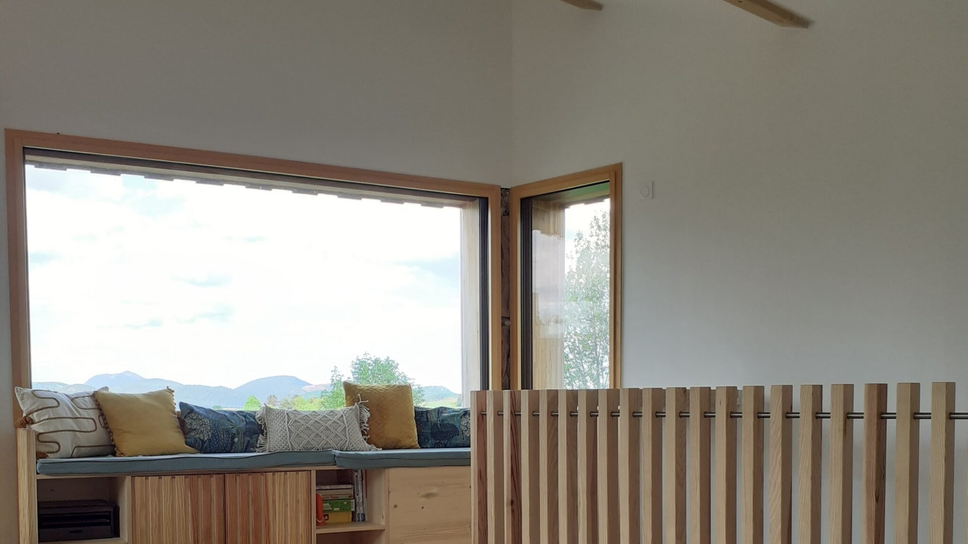 Séjour lumineux avec claustra en frêne, banquette sur mesure et parquet en chêne massif