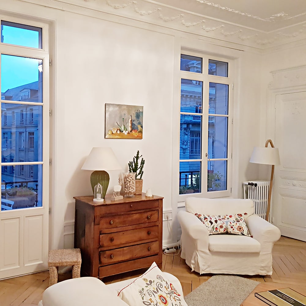 Porte-fenêtre bois à petits bois posée dans un salon au parquet ancien