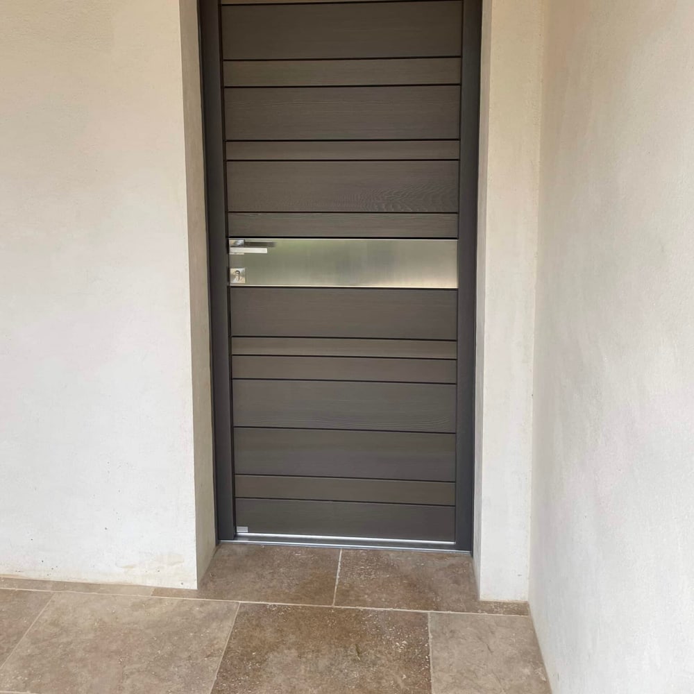 Porte d'entrée contemporaine à lames horizontales posée dans un tableau enduit