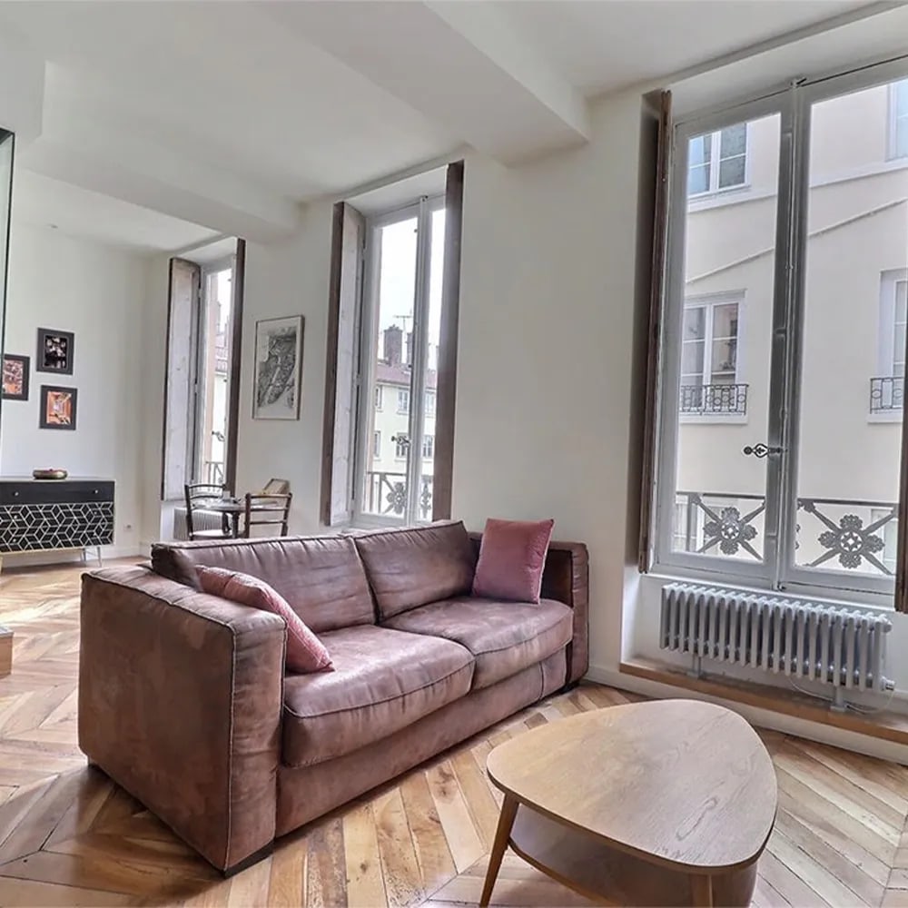 Séjour d'appartement rénové avec parquet chevron et hautes fenêtres