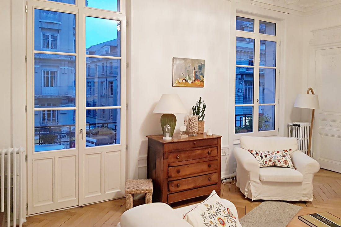 Porte-fenêtre en bois à petits bois posée dans un salon au parquet ancien