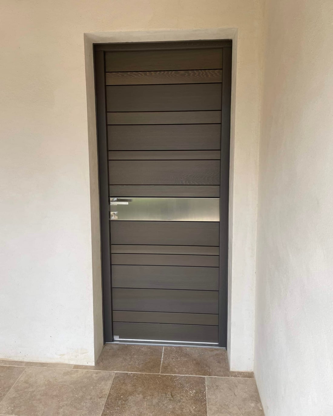 Porte d'entrée contemporaine à lames horizontales posée dans un tableau enduit